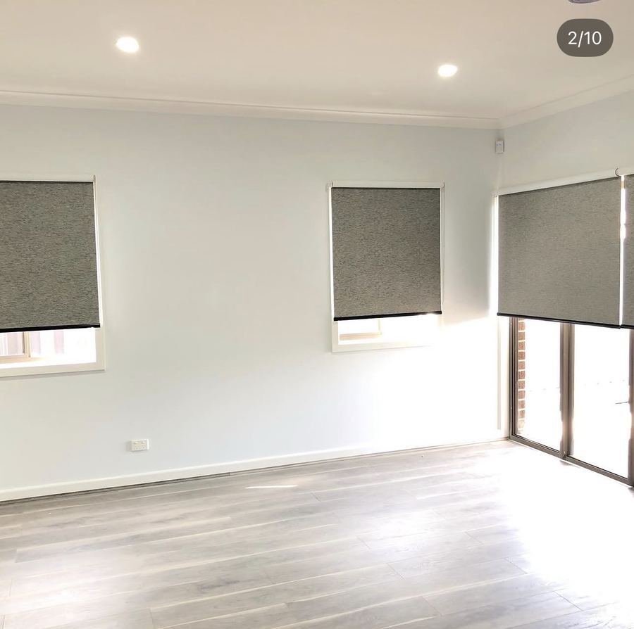 Heavy blockout roller blinds along a living room wall of windows