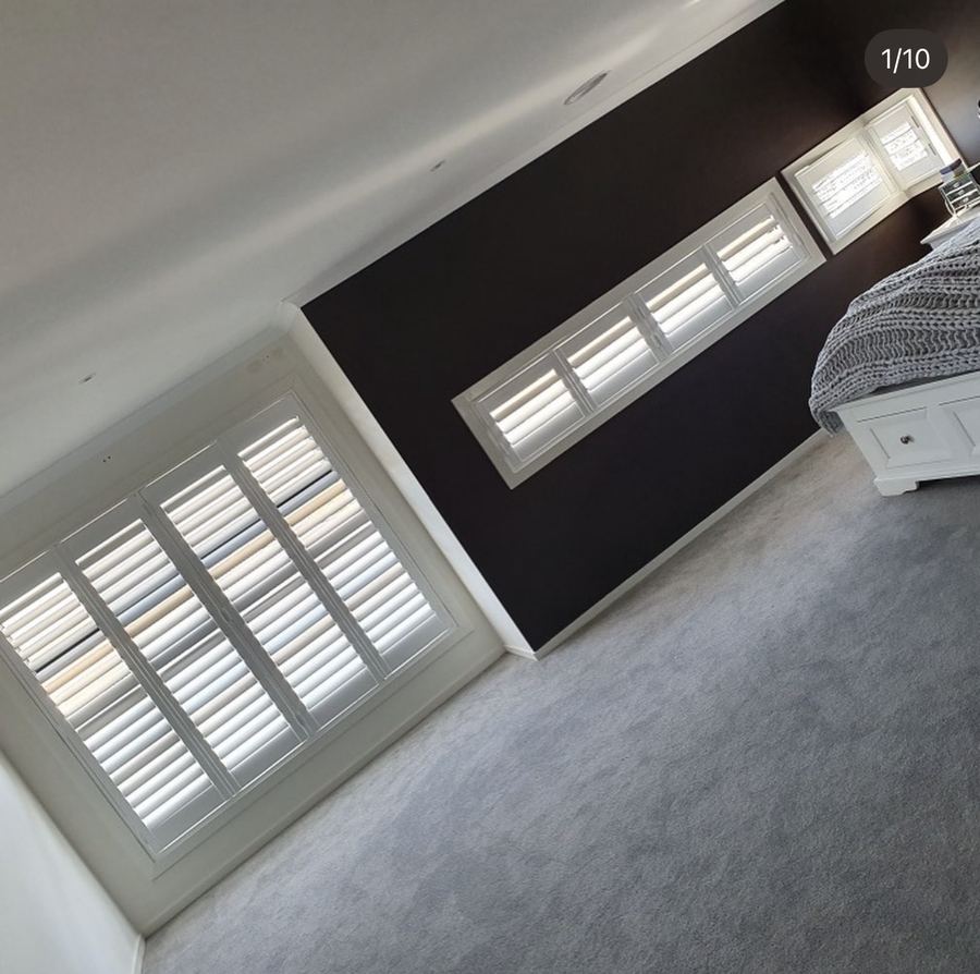 White plantation shutters along a bedroom feature wall